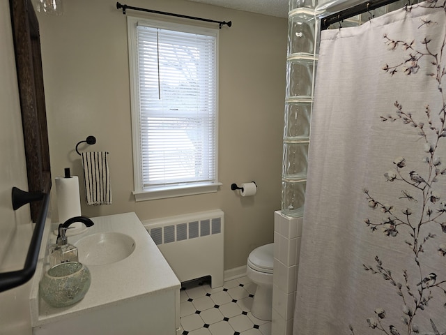 bathroom featuring vanity, radiator heating unit, toilet, and walk in shower