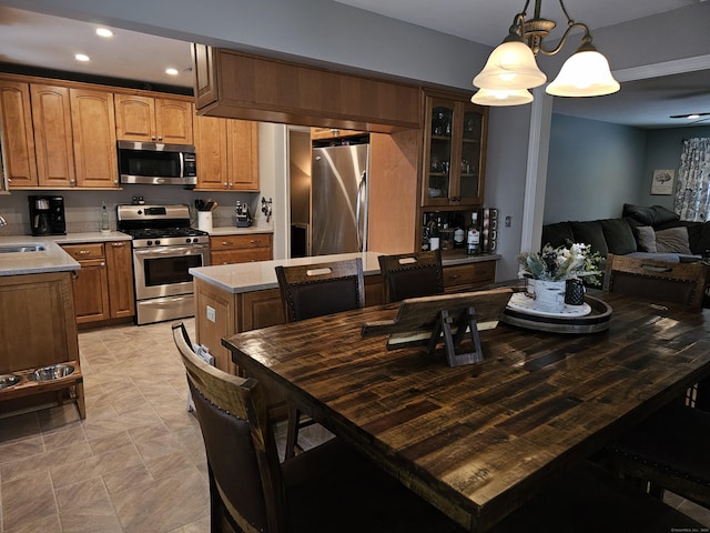 kitchen with hanging light fixtures, a kitchen island, sink, and appliances with stainless steel finishes