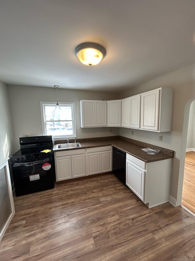 kitchen featuring dark hardwood / wood-style floors, decorative light fixtures, white cabinetry, sink, and black appliances