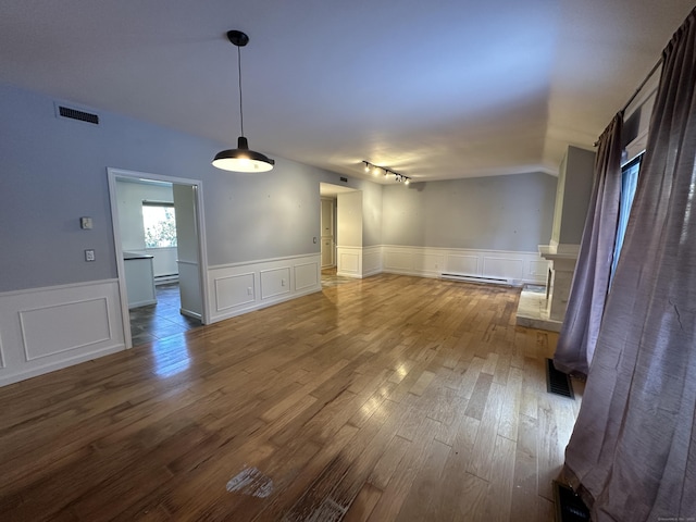 unfurnished room featuring lofted ceiling, wood-type flooring, and a baseboard heating unit