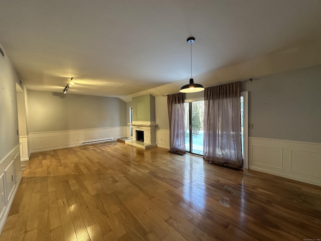 unfurnished living room with wood-type flooring, vaulted ceiling, and baseboard heating