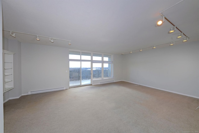 carpeted spare room with track lighting and a baseboard heating unit