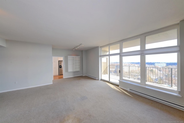 carpeted empty room with a baseboard heating unit and track lighting