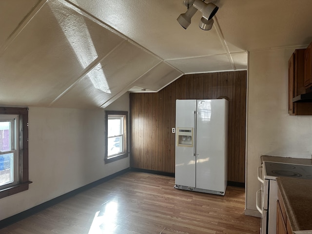 additional living space featuring wooden walls, vaulted ceiling, and light wood-type flooring