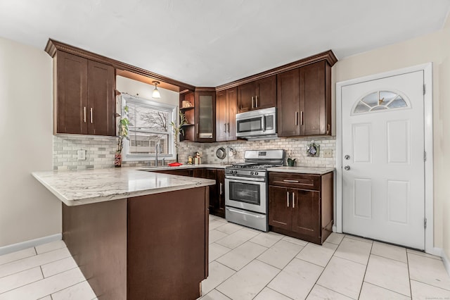 kitchen with stainless steel appliances, kitchen peninsula, dark brown cabinets, and backsplash