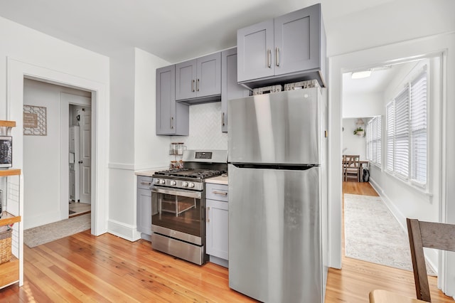 kitchen with gray cabinets, appliances with stainless steel finishes, backsplash, and light hardwood / wood-style floors