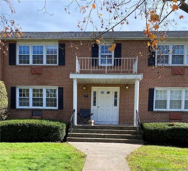 view of front of home featuring a balcony and a front lawn