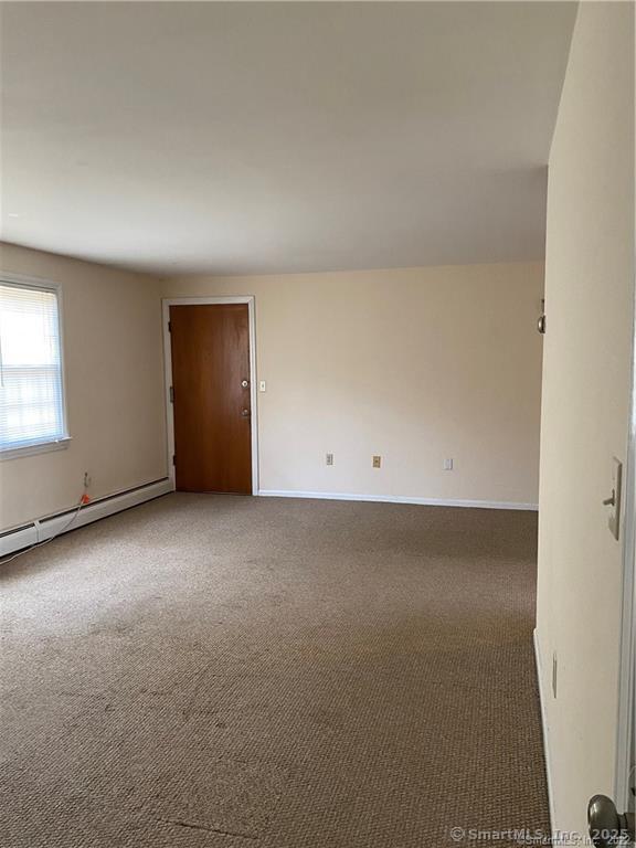 carpeted spare room with a baseboard radiator