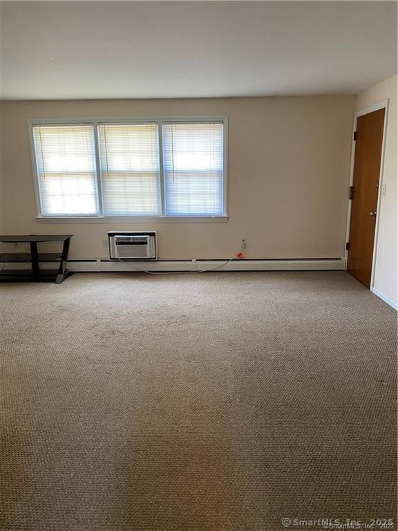 empty room with a baseboard heating unit and carpet flooring