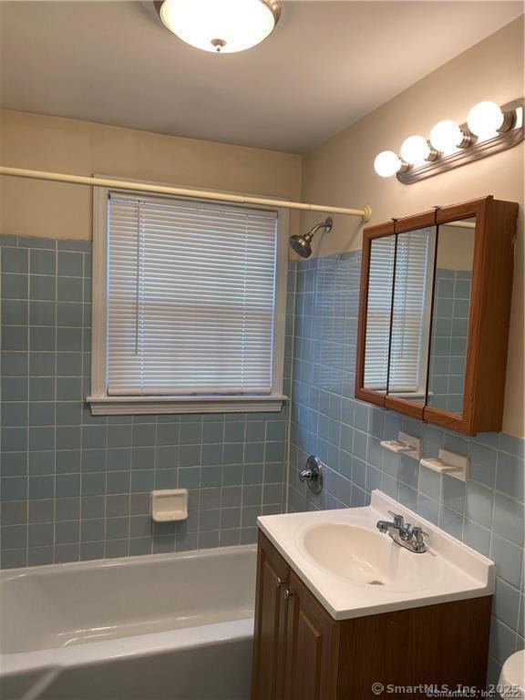 bathroom featuring vanity, tiled shower / bath combo, and tile walls