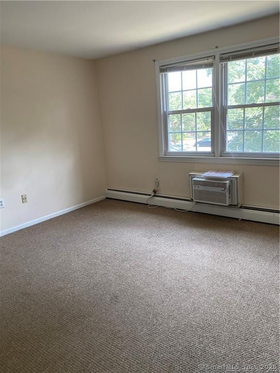 carpeted spare room with a baseboard heating unit