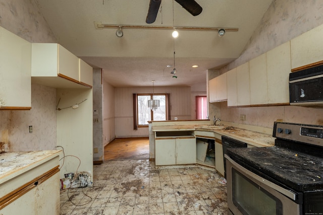 kitchen featuring sink, decorative light fixtures, kitchen peninsula, cream cabinets, and black appliances