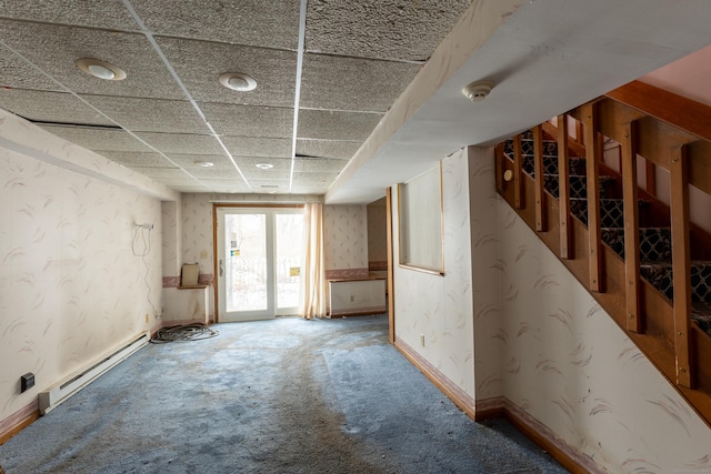 carpeted empty room with a drop ceiling and baseboard heating