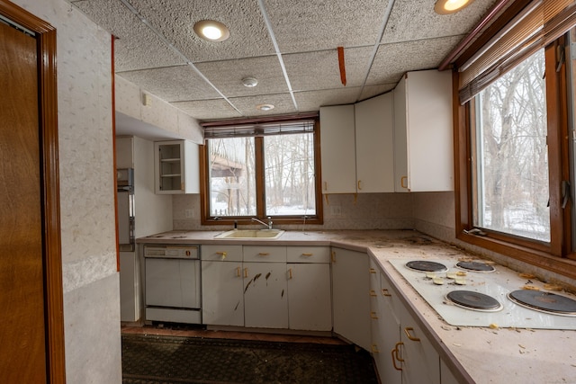 kitchen featuring white cabinetry, white appliances, sink, and a drop ceiling