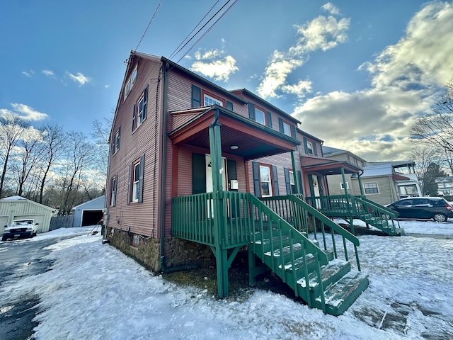 view of front of house with a garage, a porch, and an outbuilding