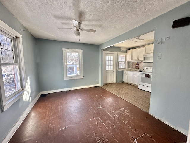 unfurnished living room featuring a textured ceiling, dark hardwood / wood-style floors, and ceiling fan