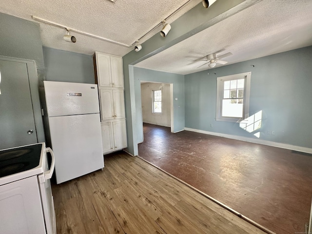 kitchen with hardwood / wood-style flooring, a textured ceiling, white cabinets, and white appliances