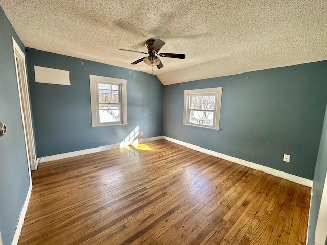 spare room featuring hardwood / wood-style flooring, plenty of natural light, lofted ceiling, and a textured ceiling