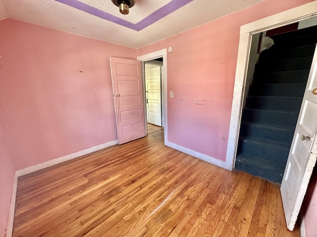 unfurnished room featuring lofted ceiling, light hardwood / wood-style flooring, and a textured ceiling