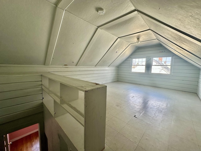 additional living space featuring lofted ceiling and wood walls