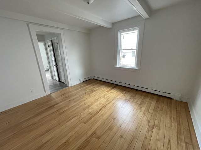 spare room featuring wood-type flooring, a baseboard radiator, and beamed ceiling