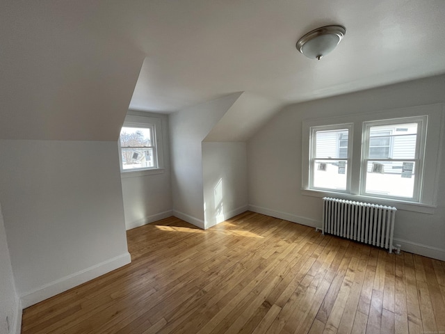 additional living space featuring lofted ceiling, radiator, and light hardwood / wood-style floors