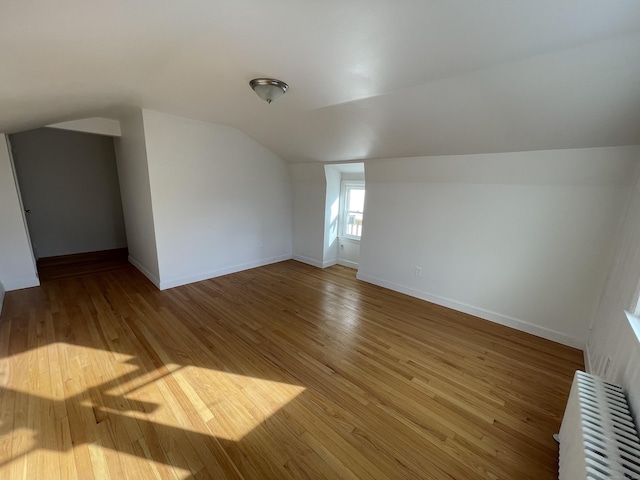 bonus room with lofted ceiling, radiator, and wood-type flooring