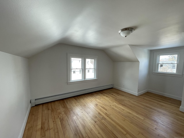 additional living space featuring a baseboard radiator, vaulted ceiling, and light wood-type flooring