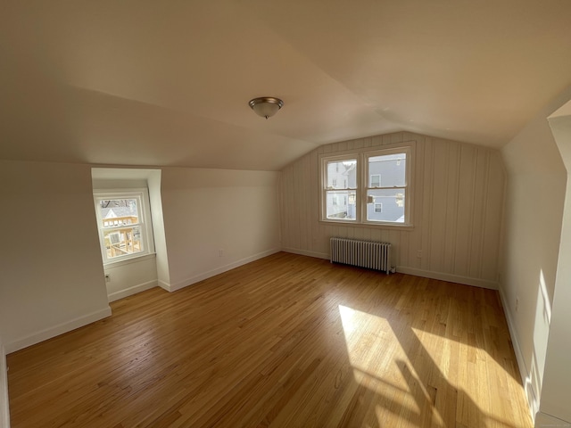 bonus room featuring vaulted ceiling, radiator, and light hardwood / wood-style flooring