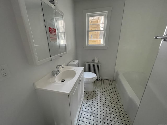 bathroom with vanity, a tub to relax in, radiator heating unit, and toilet