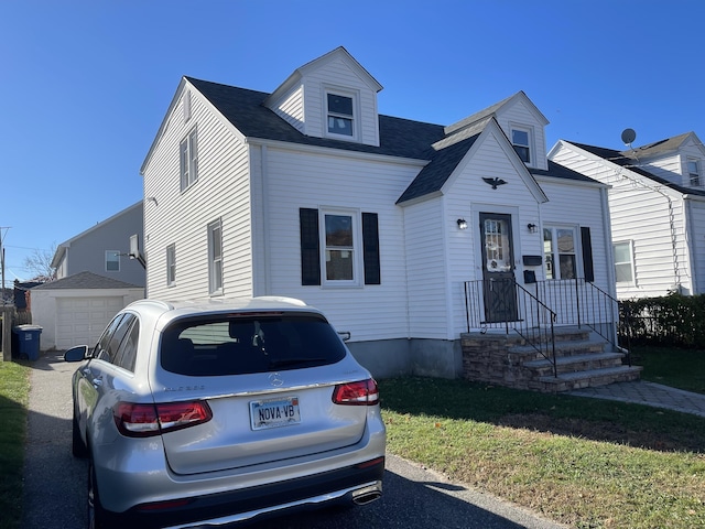 view of front facade with a garage, an outbuilding, and a front lawn