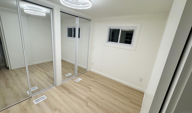 unfurnished bedroom featuring multiple closets and light wood-type flooring