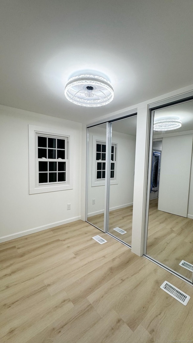 unfurnished bedroom with light wood-type flooring and two closets