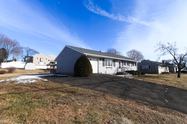 view of front facade featuring a garage, a storage shed, and a front lawn