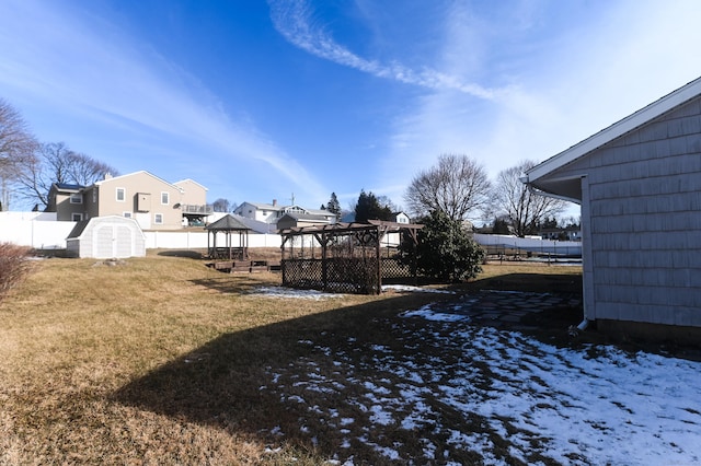 yard layered in snow with a storage shed and a gazebo