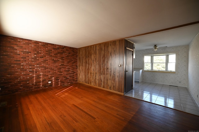 unfurnished room with brick wall, ceiling fan, and light hardwood / wood-style flooring