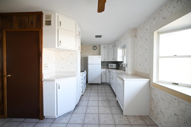 kitchen featuring white cabinetry, sink, white appliances, and light tile patterned floors