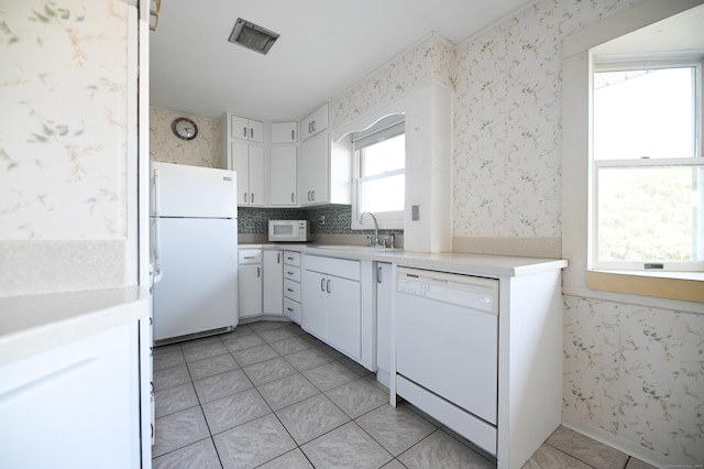 kitchen with white cabinetry, sink, white appliances, and light tile patterned floors