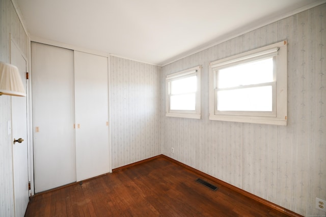 unfurnished bedroom with dark hardwood / wood-style flooring and a closet