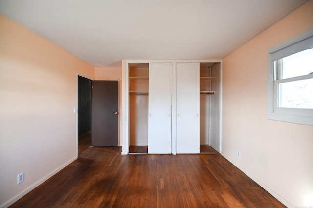 unfurnished bedroom with dark wood-type flooring and two closets