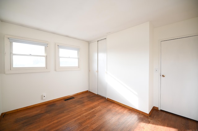 unfurnished bedroom with dark hardwood / wood-style flooring and a closet