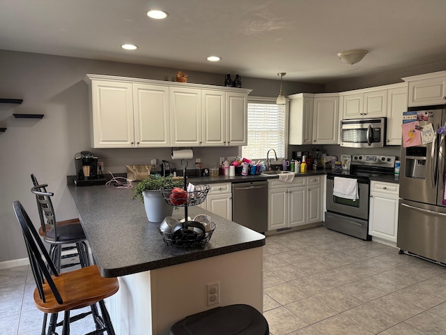 kitchen featuring a breakfast bar, white cabinetry, sink, kitchen peninsula, and stainless steel appliances