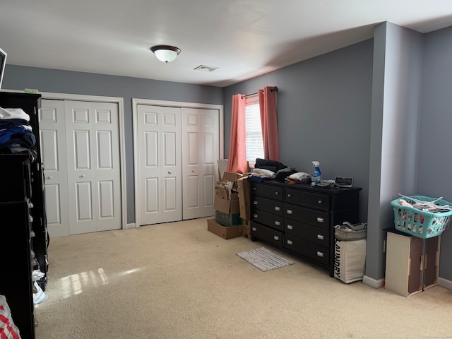 bedroom featuring two closets and light colored carpet