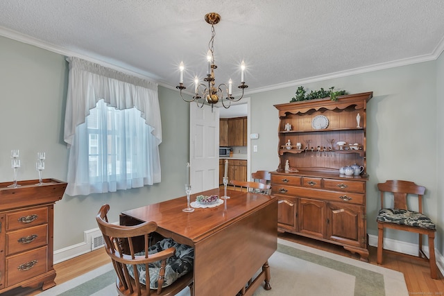 dining area featuring crown molding, a textured ceiling, a chandelier, and light wood-type flooring