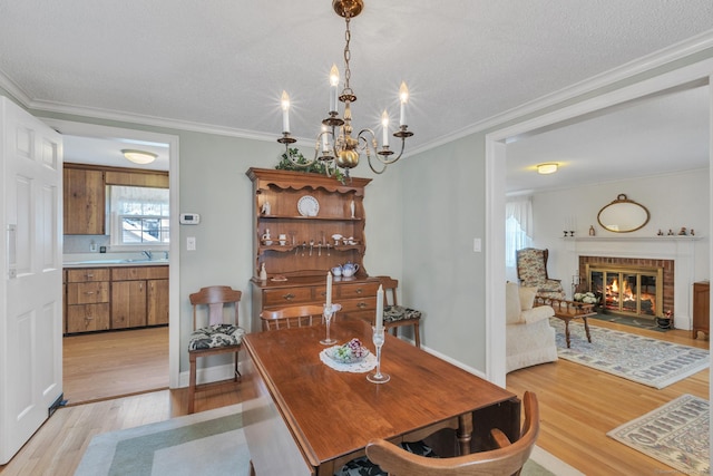 dining room with crown molding, a brick fireplace, sink, and light hardwood / wood-style flooring