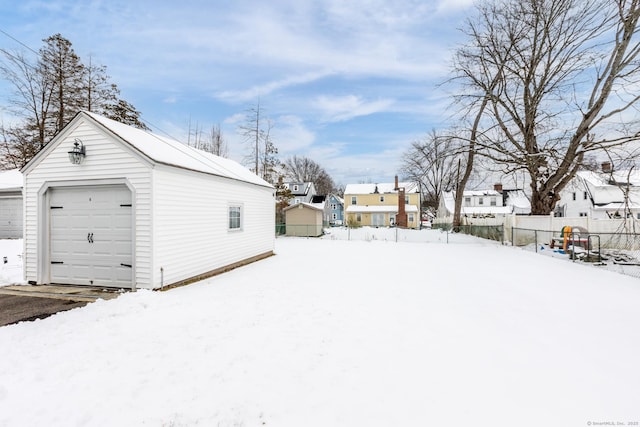 snowy yard with a garage and an outbuilding