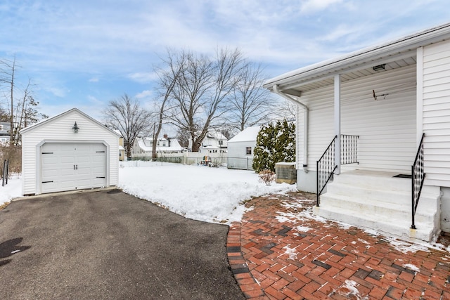 yard layered in snow featuring a garage and an outdoor structure