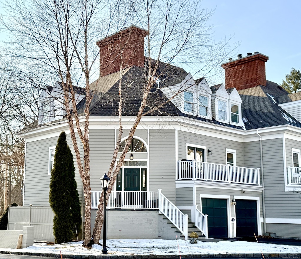 new england style home featuring a garage and a balcony