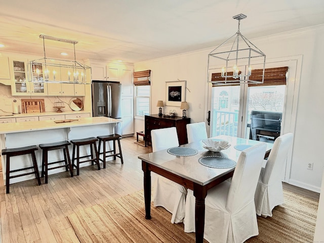 dining area featuring an inviting chandelier, ornamental molding, light hardwood / wood-style floors, and a wealth of natural light