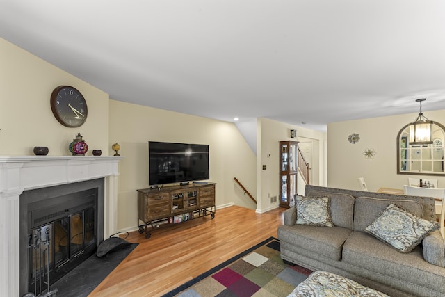 living area featuring wood finished floors, stairway, a fireplace with flush hearth, and baseboards